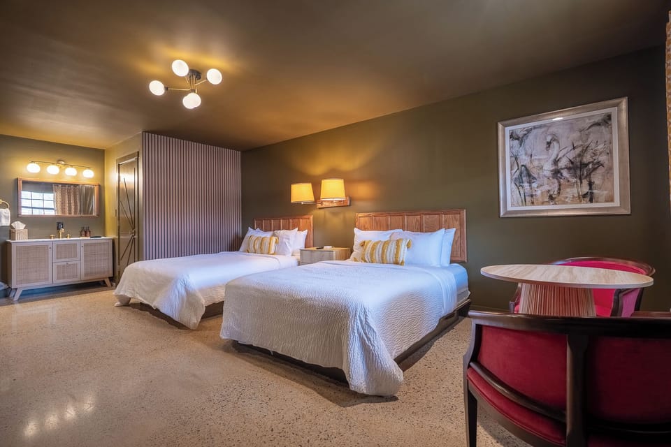 2 queen beds with sitting area for 2, TV console, smart TV, bookcase with hot water kettle, french press, microwave, mini fridge, sink vanity with towels and wash cloths