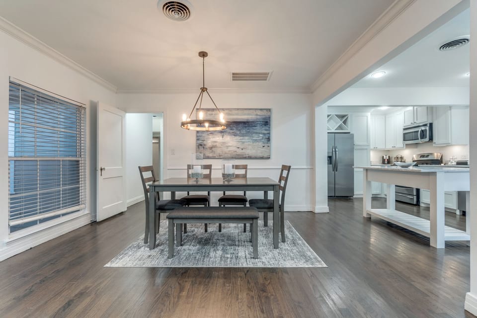 Gather around your elegant dining table for memorable meals, with rich hardwood floors and modern pendant lighting creating warmth throughout your open living space.