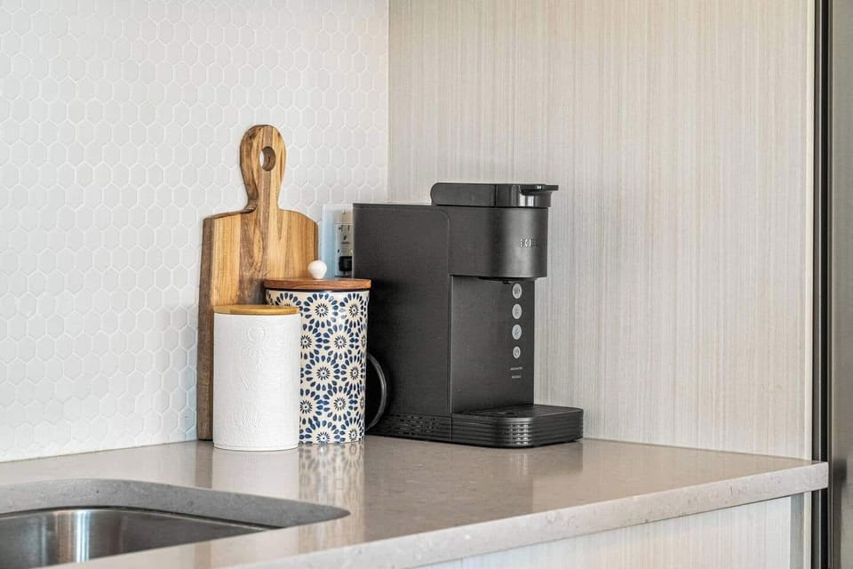 Start your mornings right with a fresh brew from the sleek Keurig coffee station, complete with stylish canisters and modern touches to elevate your kitchen experience.