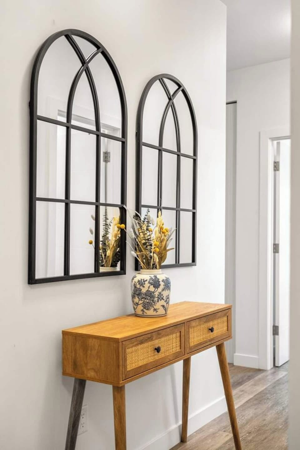 A warm and welcoming entryway, this charming console setup with arched mirrors and a floral vase adds timeless elegance and a perfect first impression.