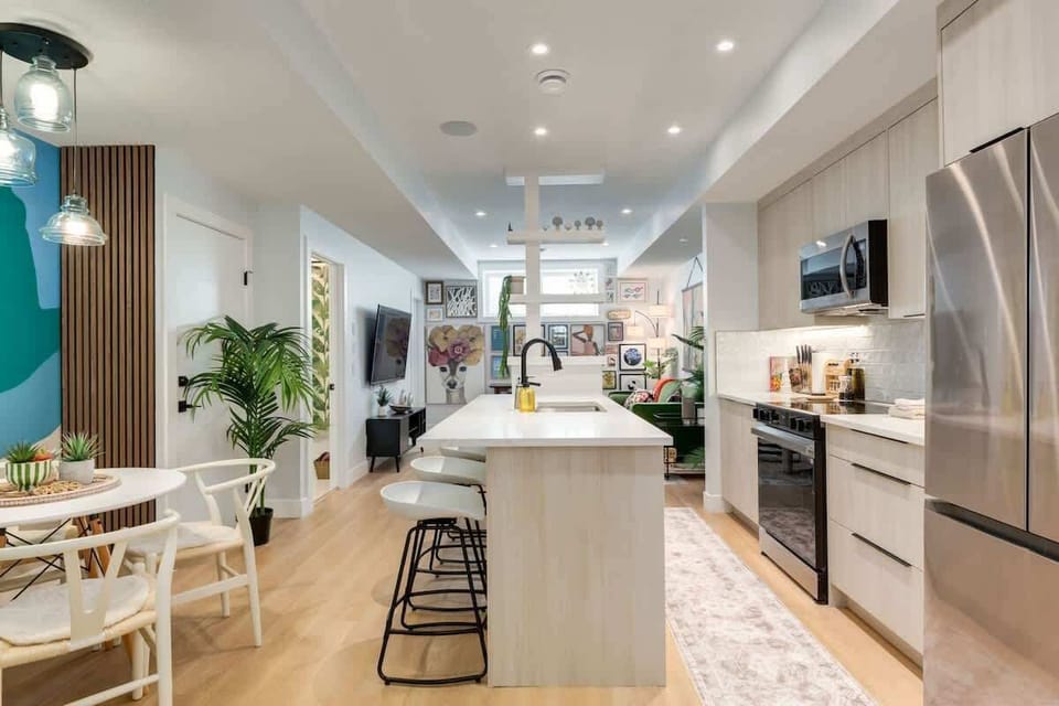 Full view of open-concept kitchen with sleek white cabinetry and breakfast bar