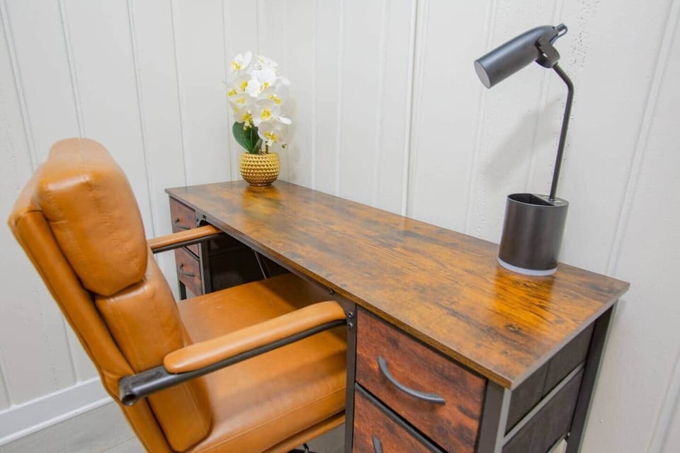 This great workspace features a desk with drawer storage, a sleek modern lamp for focused lighting, and a comfortable leather chair for long work sessions. 
