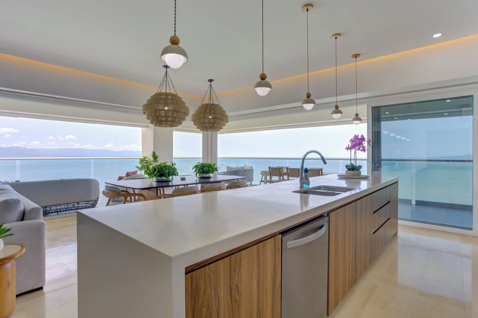 Prep cocktails on a stunning, waterfall-edge quartz kitchen island, fully loaded with professional stainless-steel appliances.