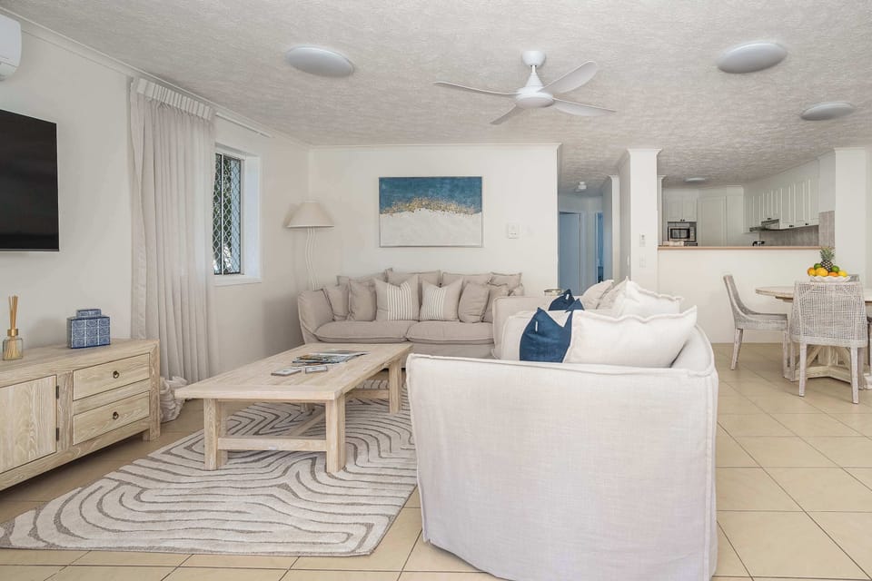 Living room has sheer blinds, ceiling fan, air-conditioning and wall mounted 55" Smart TV with a moveable wall bracket