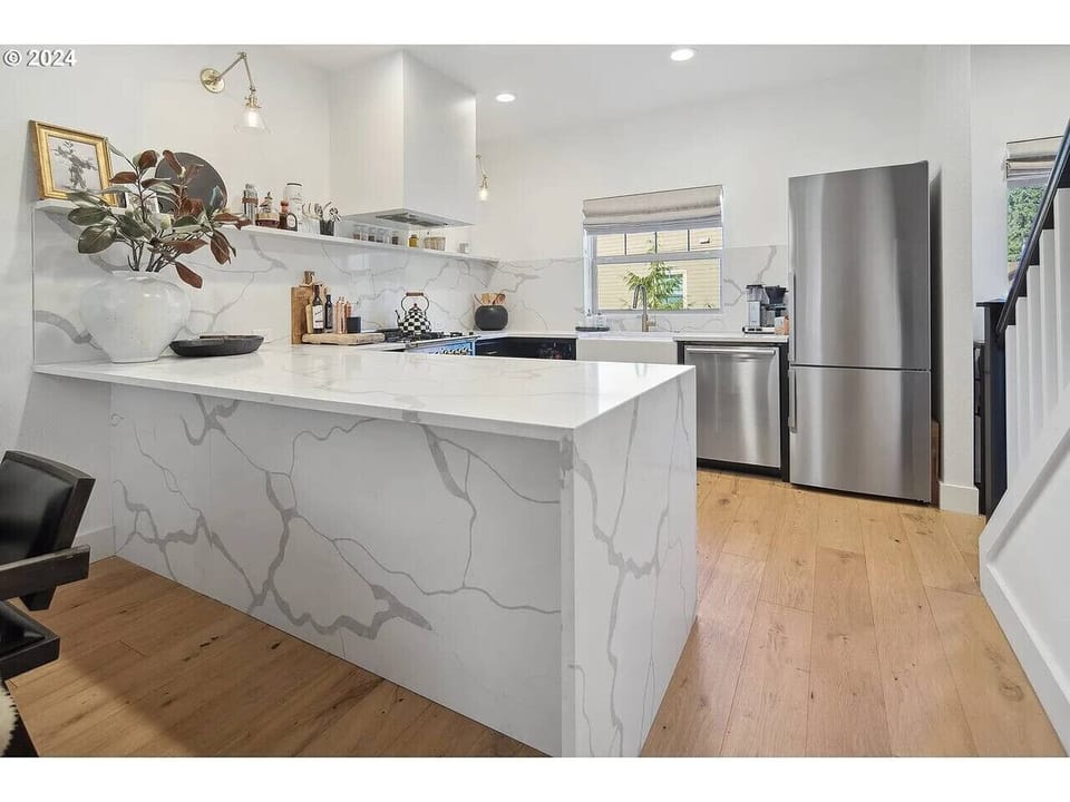Gourmet kitchen with waterfall granite island, high-end stainless appliances, and bright modern design — perfect for cooking and entertaining.