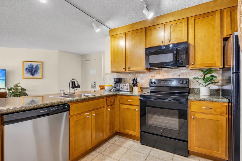 Fully equipped kitchen with black and stainless steel appliances, and warm cabinetry