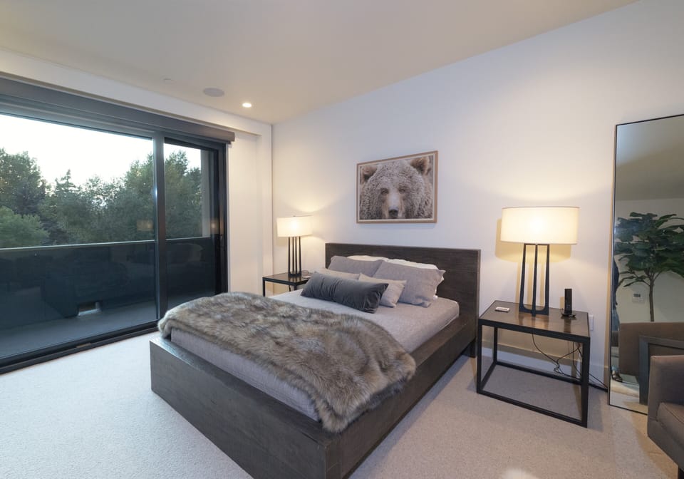 Unwind in your serene retreat where modern elegance meets comfort. Sink into the plush bed with cozy faux fur throw as natural light filters through floor-to-ceiling windows.
