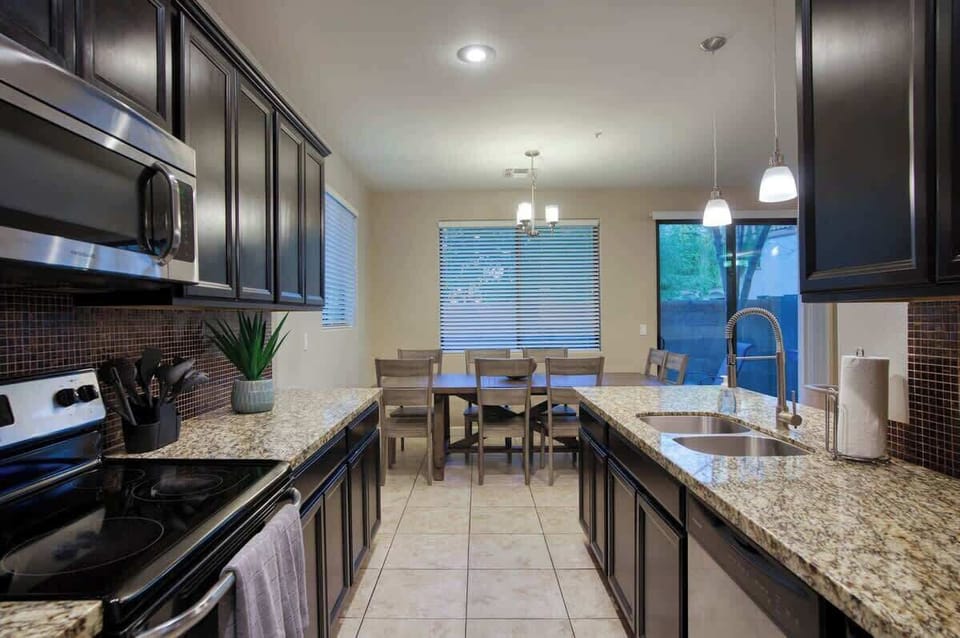 Modern kitchen with granite countertops, stainless steel sink, and an open dining area