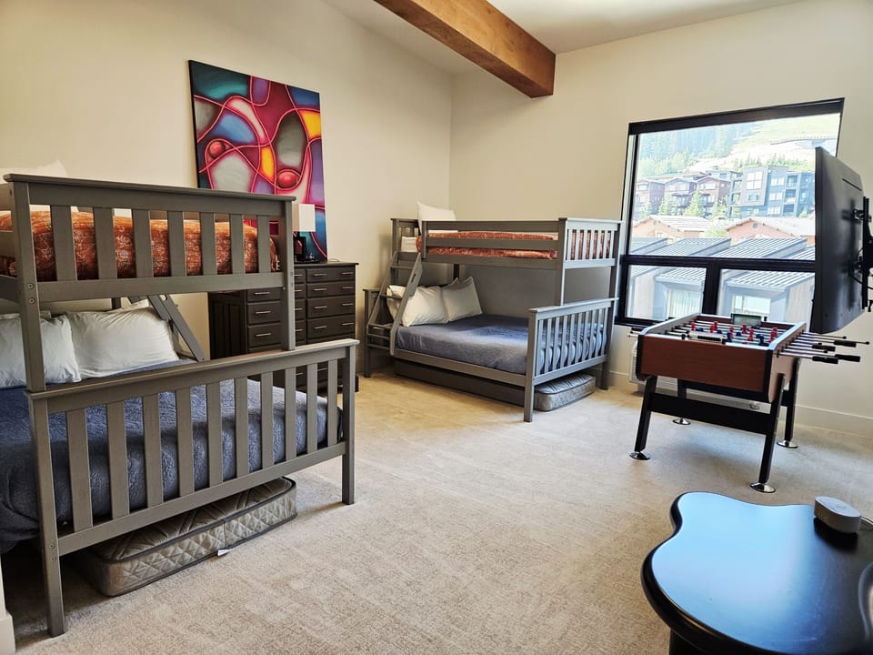 Bunk room with two full size beds, two twins, a fooseball table and tv