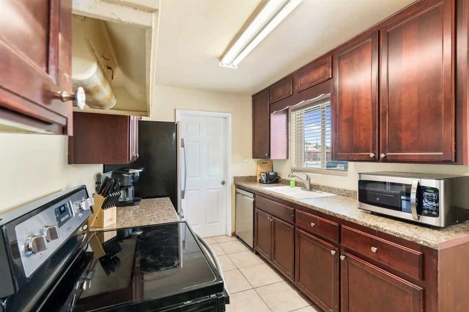 Bright kitchen with warm wood cabinets, a black stove, microwave, and long countertop ready for prepping meals. The layout keeps everything within reach, making it easy to cook, plate, and gather around the nearby dining area.
