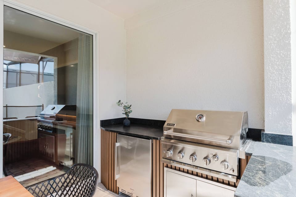 Step outside to your outdoor cooking oasis with a sleek stainless steel grill and dark stone countertops, perfect for culinary creativity.