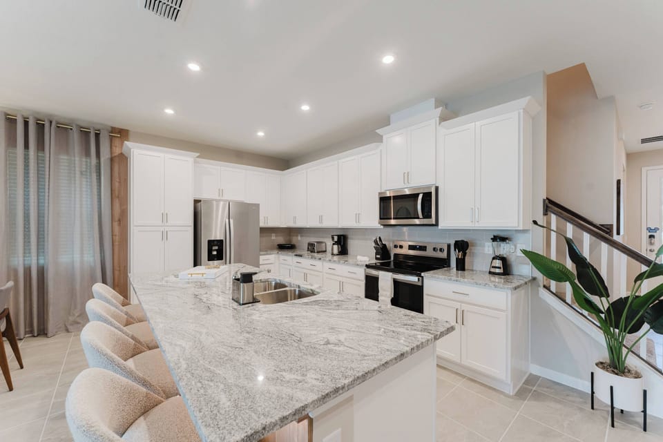 Welcome to our stylish kitchen, where sleek white cabinets and a beautiful granite island set the stage for casual meals and entertaining.