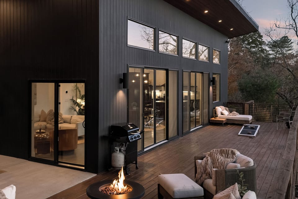 {Outdoor Lounge} The Glass House invites you to linger outside—cozy blankets, cornhole, giant Connect 4, and the forest glowing as twilight settles in. A mountain moment you won’t forget.
