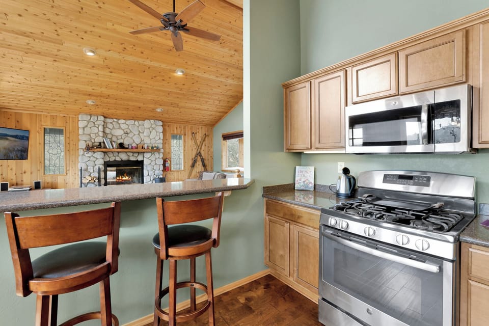 Kitchen with breakfast bar opens seamlessly to the living room, creating a warm, inviting space perfect for cooking, dining, and shared guest experiences.