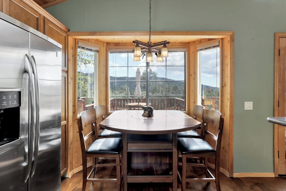 Dining area with scenic views framed by windows, offering a bright, inviting space perfect for shared meals, gatherings, and memorable guest experiences