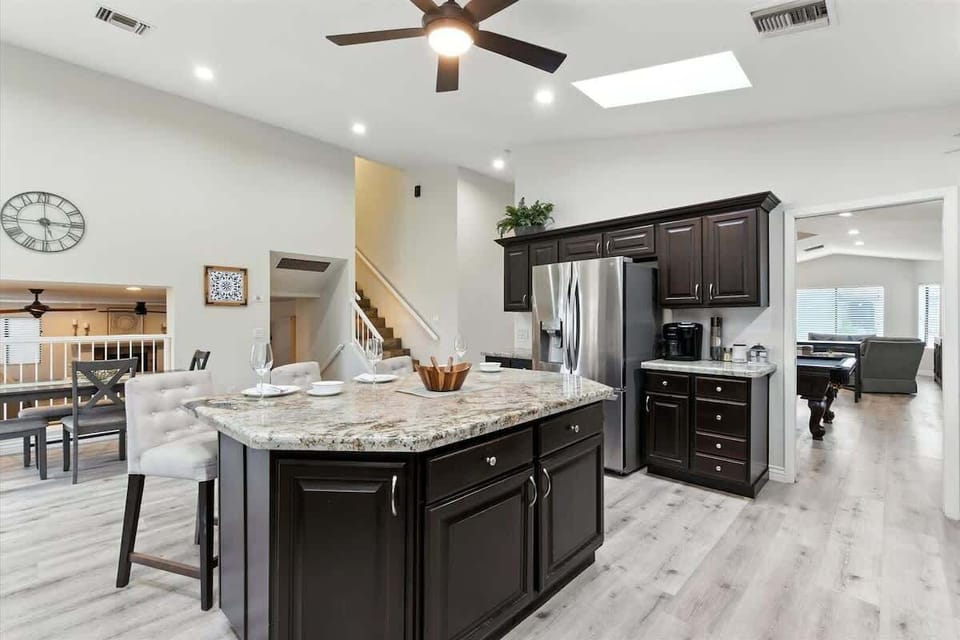 The kitchen features granite countertops, stainless steel appliances, and a spacious island with seating for family and friends.