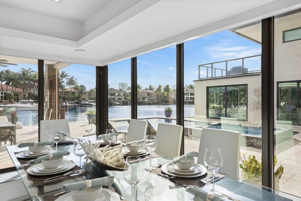Spacious formal dining area surrounded by massive windows for incredible views of the canal and pool during meals