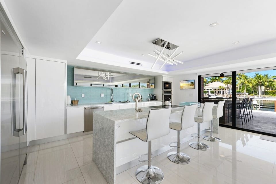 Fully equipped, family-ready modern kitchen featuring a large stone island with bar seating, premium appliances, and seamless access to the outdoor patio