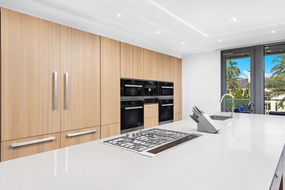 Contemporary culinary space showcasing custom wood cabinets, center island, and outdoor connection