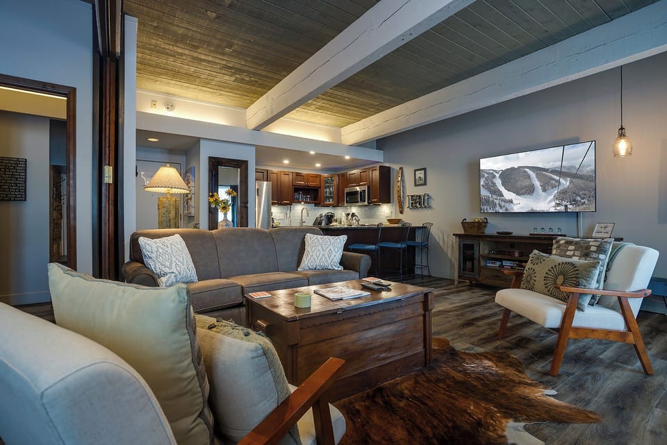 Sink into plush sofas beneath rustic beams while mountain views on the large TV transport you to alpine adventures from your cozy retreat.