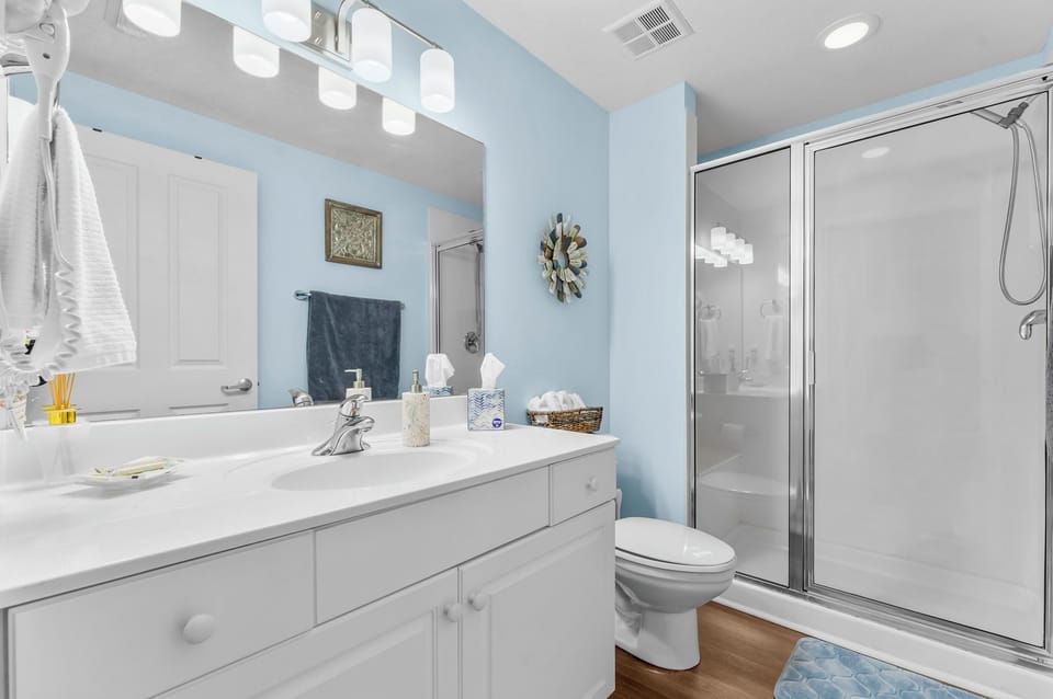 Light blue bathroom with a glass-enclosed shower and white vanity