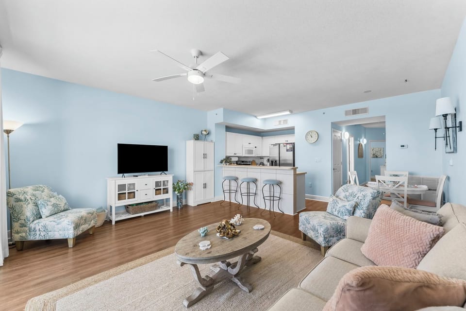 Spacious living area with soft blue walls and an open kitchen featuring a breakfast bar.