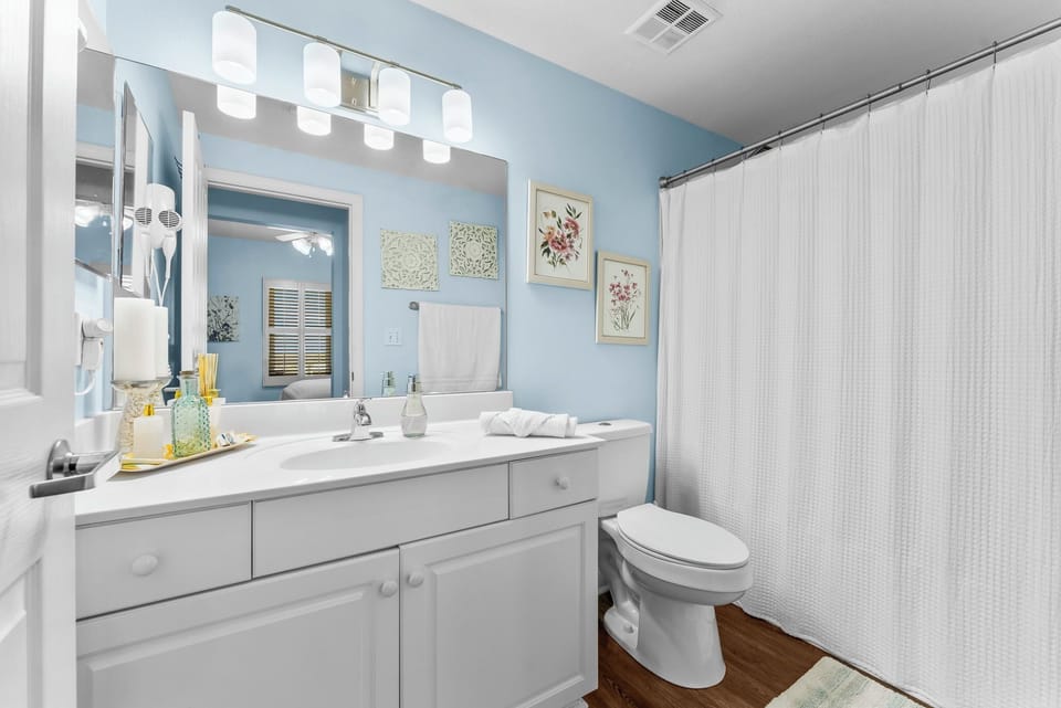 bright bathroom with white cabinetry and a large mirror