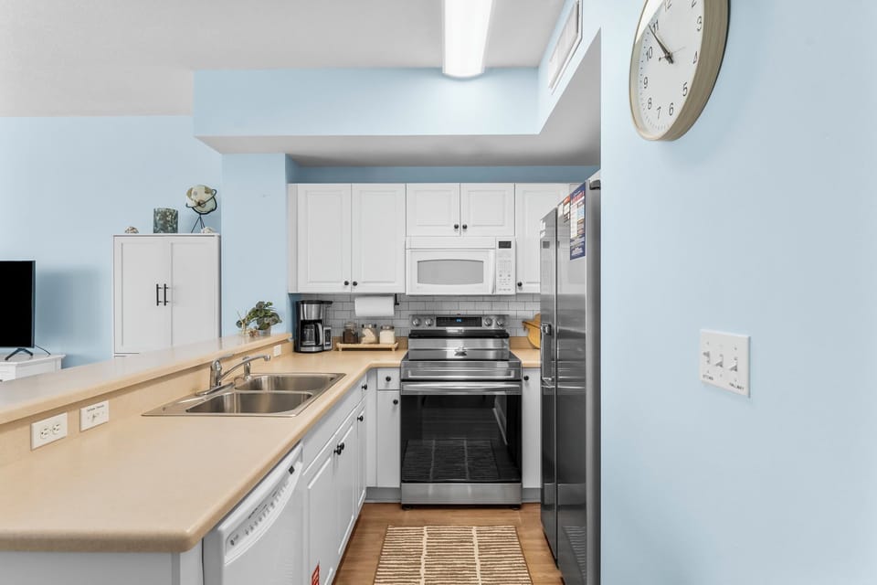 Modern kitchen with stainless steel appliances and light blue walls.