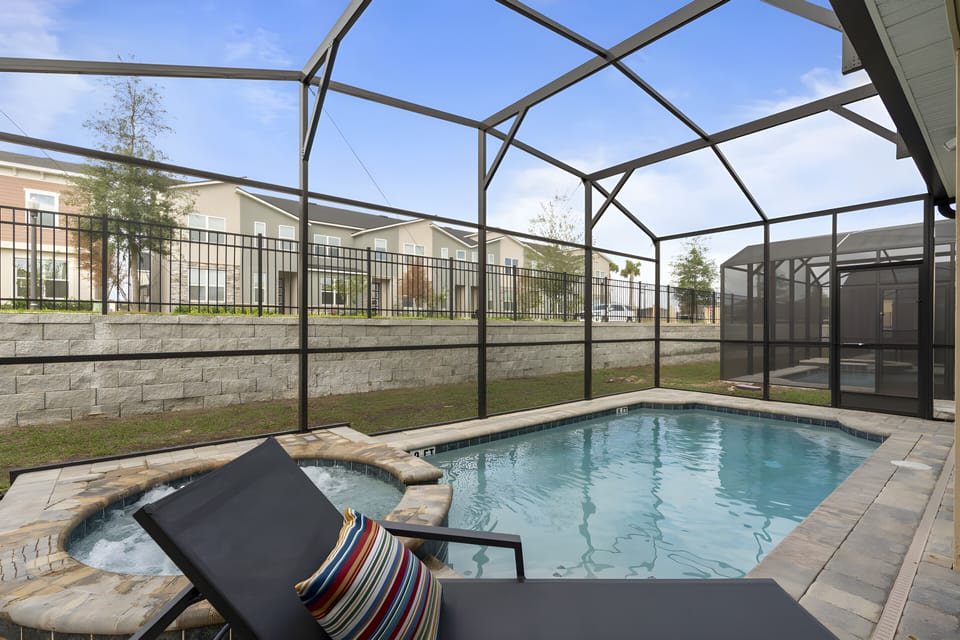 Step outside to your private oasis, featuring a sparkling pool framed by a sleek enclosure. Relax on a lounge chair, adorned with vibrant cushions, while the sunlight dances on the water, creating a perfect backdrop for your stay.