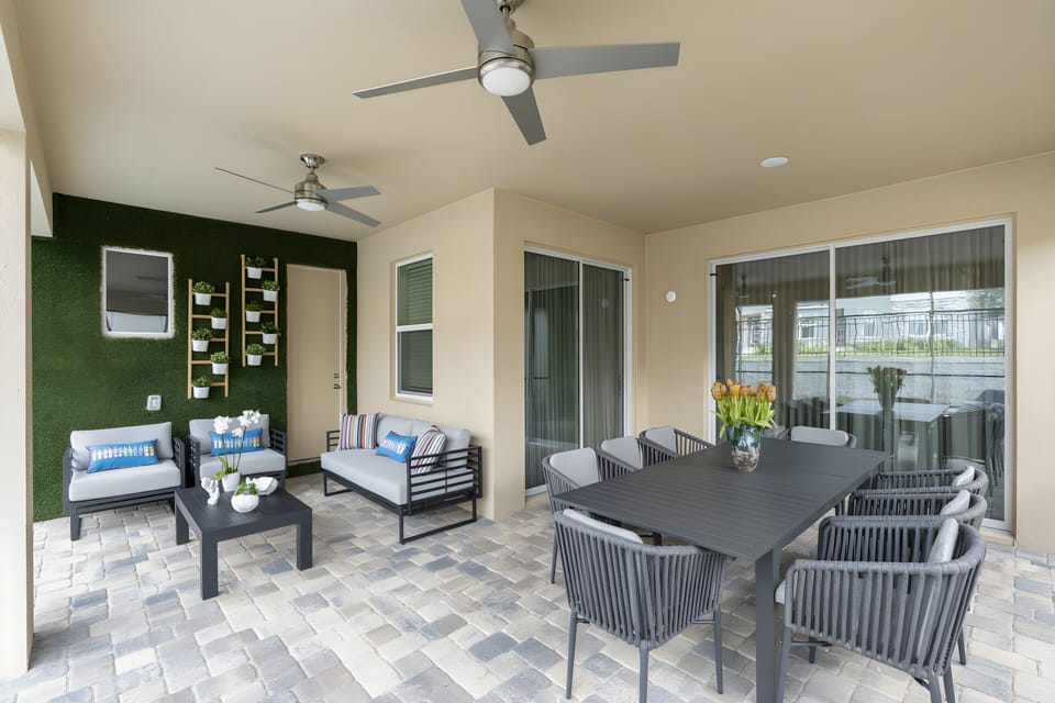 Enjoy our inviting outdoor lounge with a stylish dining table and woven chairs. The soft green accent wall enhances the natural vibe, and large windows fill the space with light, making it ideal for relaxed meals and gatherings.
