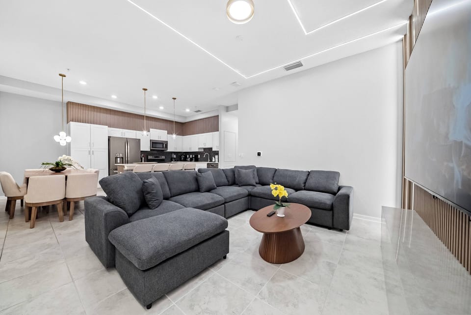 Enjoy a cozy stay in this spacious living area, featuring a plush gray sectional sofa for ultimate relaxation. The marble flooring reflects natural light, and the modern decor creates a warm atmosphere ideal for gatherings.