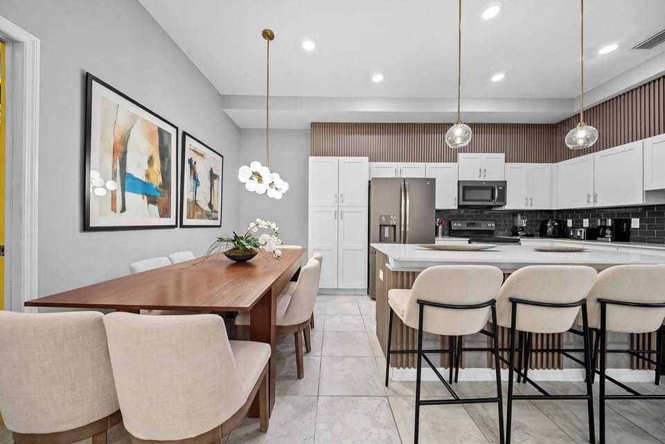 Enjoy a stylish kitchen and dining area featuring sleek white cabinetry and warm wood accents. The elegant dining table is perfect for shared meals, and modern pendant lights add a touch of charm to the space.