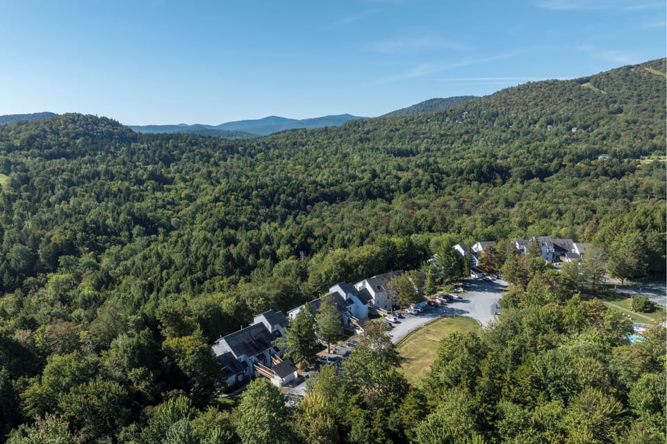 Condo complex surrounded by lush trees and rolling Vermont mountains