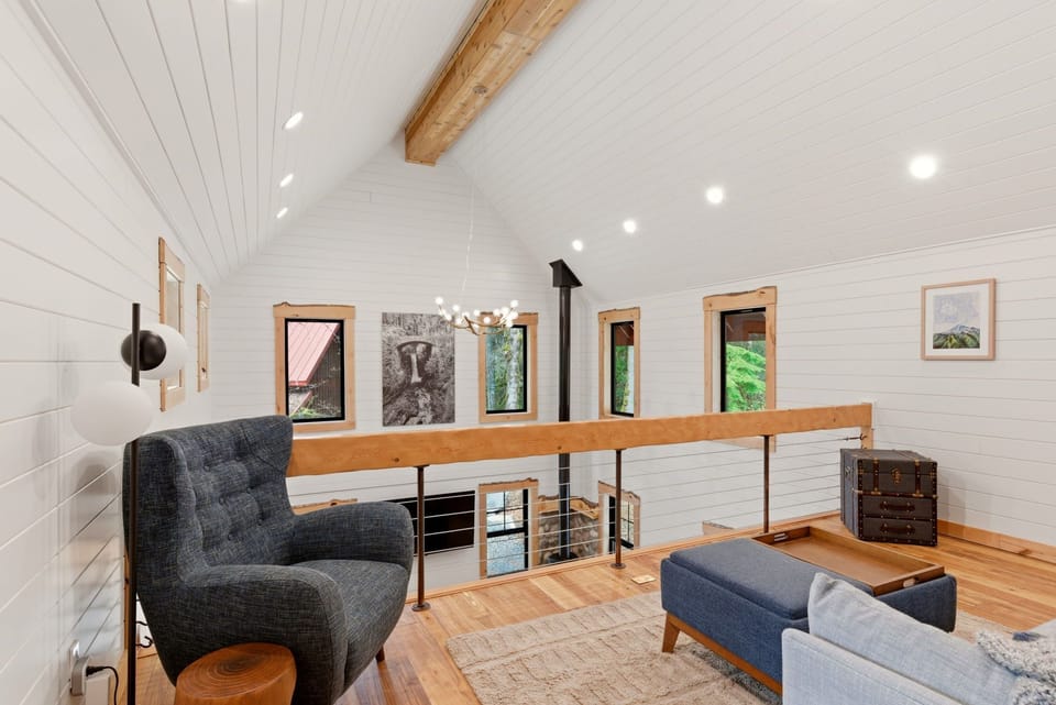 A serene loft lounge overlooking the living room — ideal for reading, journaling, or taking in the treetop views.
