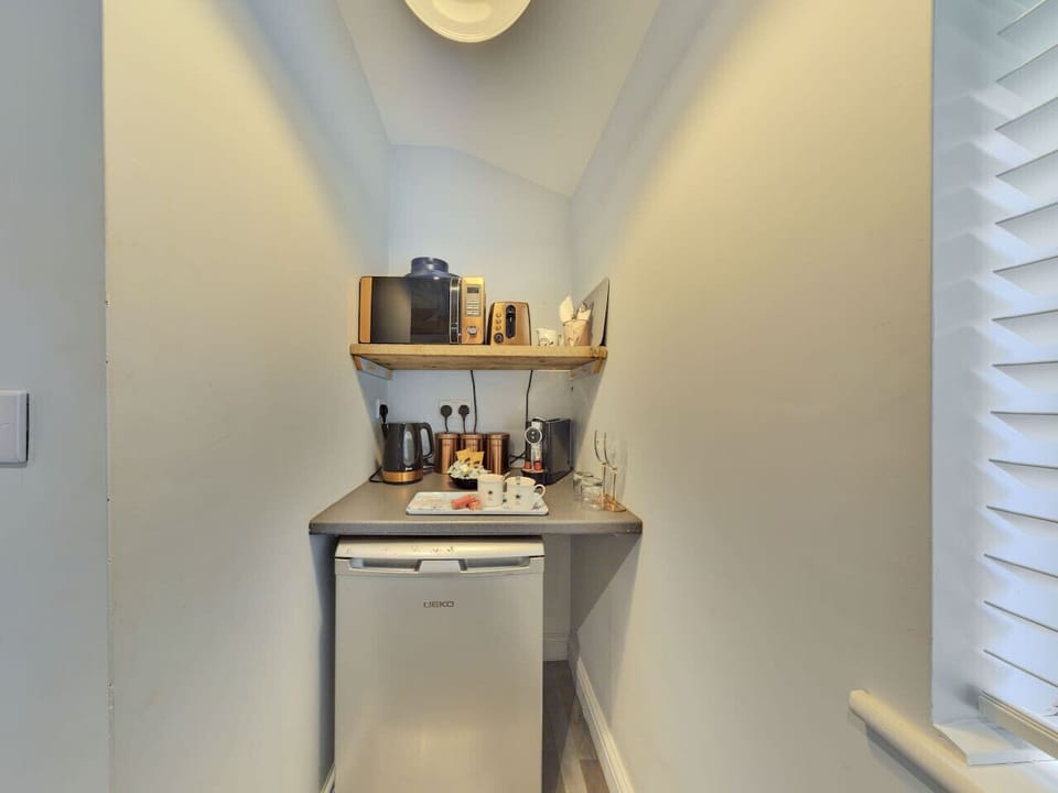 Compact kitchenette with fridge, kettle, and utensils