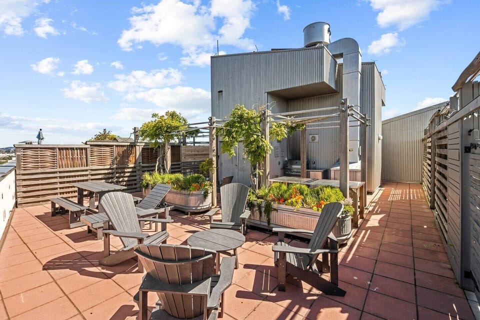 Shared rooftop deck featuring outdoor lounge seating and wide-open city and harbor views.