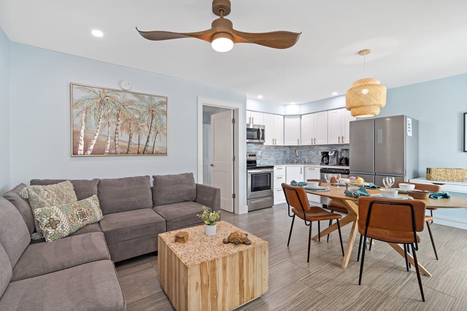 Sea Breeze's Living Area, Featuring a Pull-Out Sleeper Couch, A Dining Table, A Fully Stocked Kitchen, and a Desk.