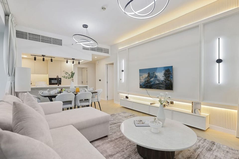 Stylish living room with soft beige tones and open kitchen-dining layout.
