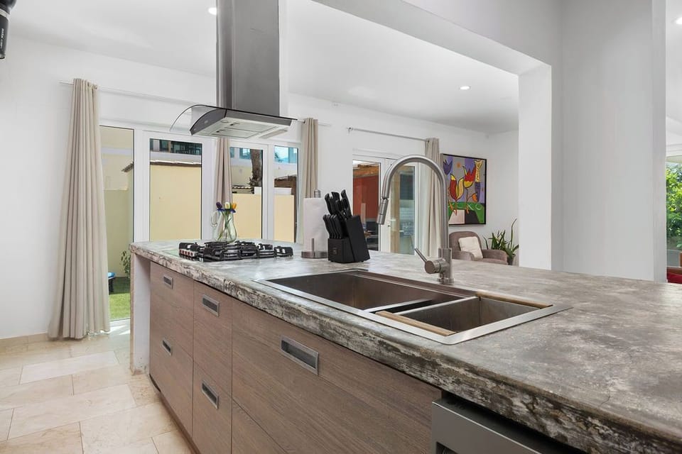 Your open-concept kitchen features sleek modern finishes, gas cooktop, and spacious countertops—perfect for preparing meals while staying connected to the living areas and garden views beyond.