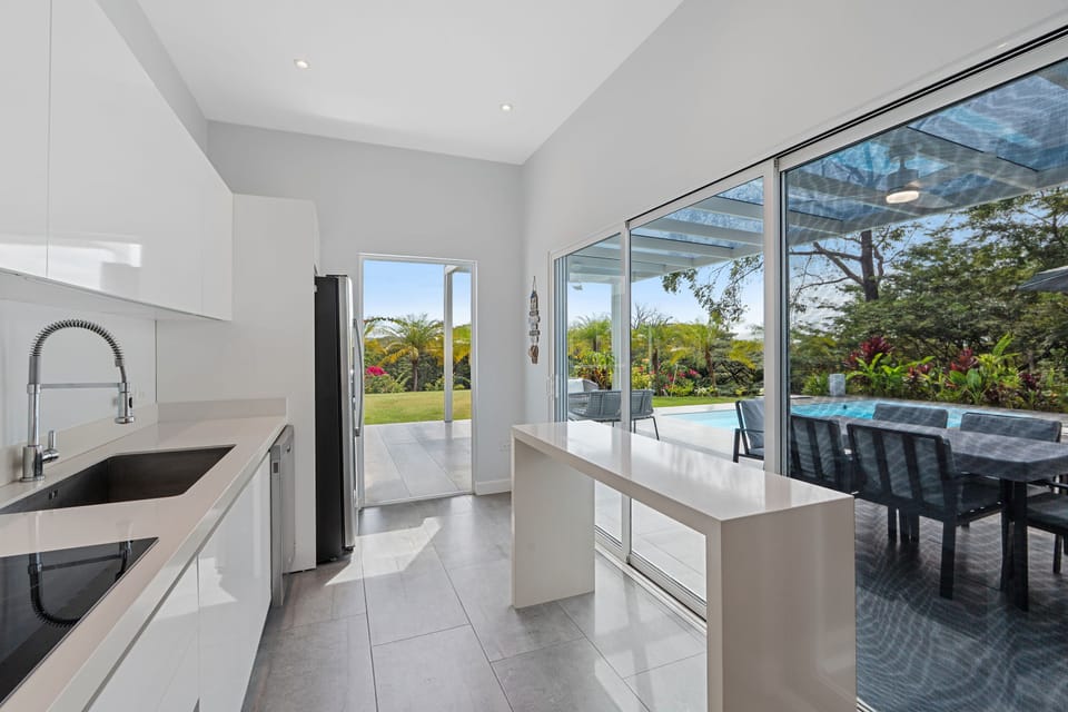 Modern kitchen with high-end finishes and glass doors opening to the pool.