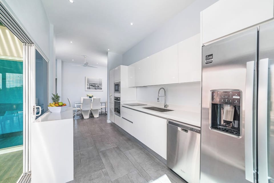 Bright open kitchen with stainless steel appliances, opening to dining & pool.