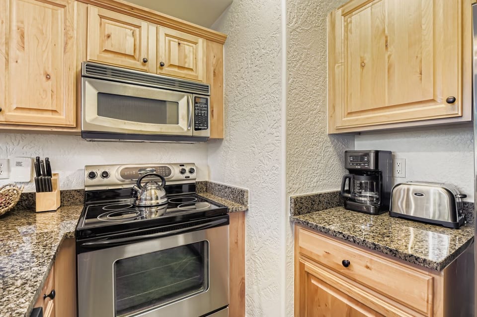 This chef-ready kitchen at Silverado Lodge features warm alder cabinetry, sleek granite countertops, and stainless steel appliances. The spacious breakfast bar is perfect for après-ski dining and entertainin
