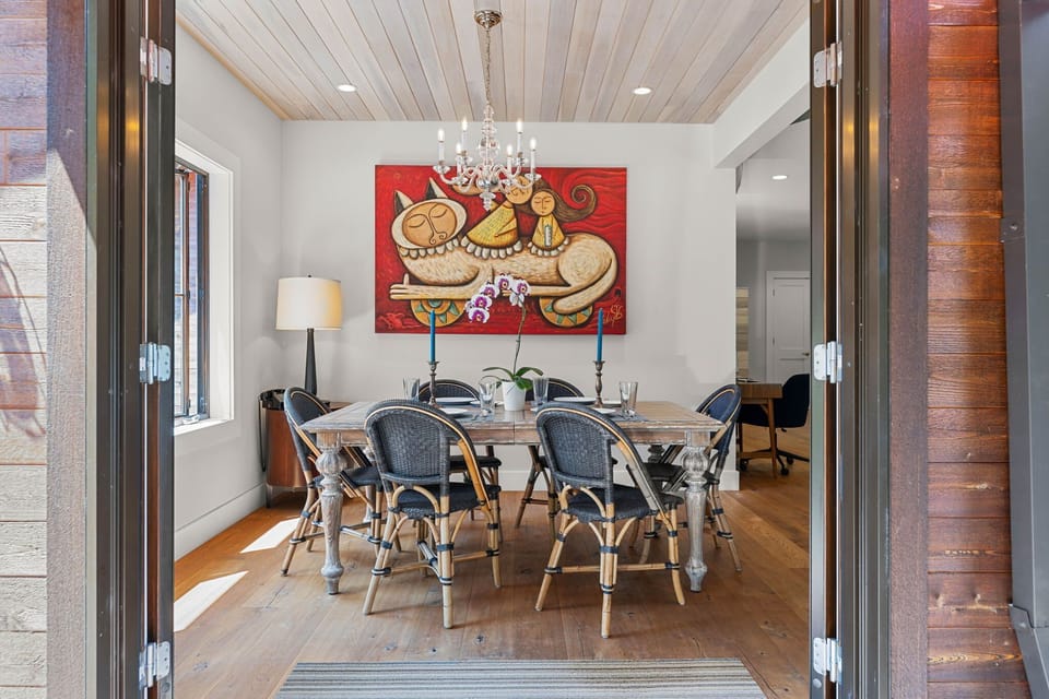 Dining table beneath a chandelier beside the patio doors.