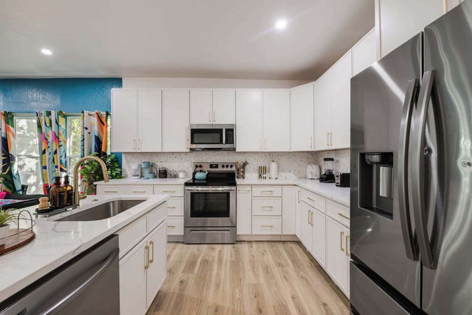 Bright modern kitchen with sleek white cabinets, stainless steel appliances, and plenty of counter space for cooking and entertaining.