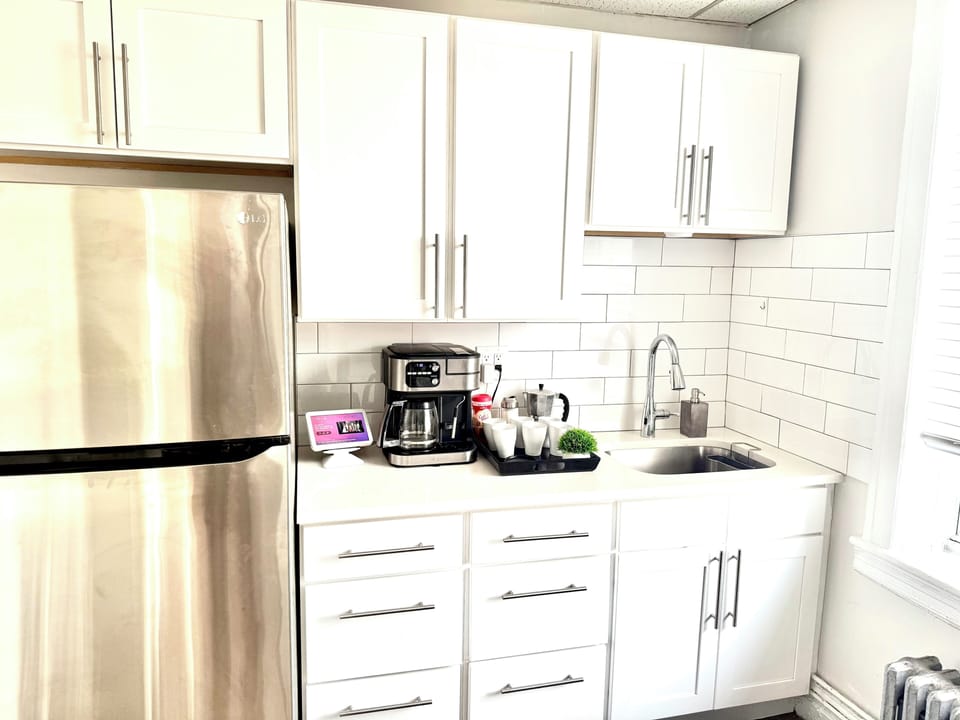 Bright modern kitchen with stainless fridge, coffee station, subway tile