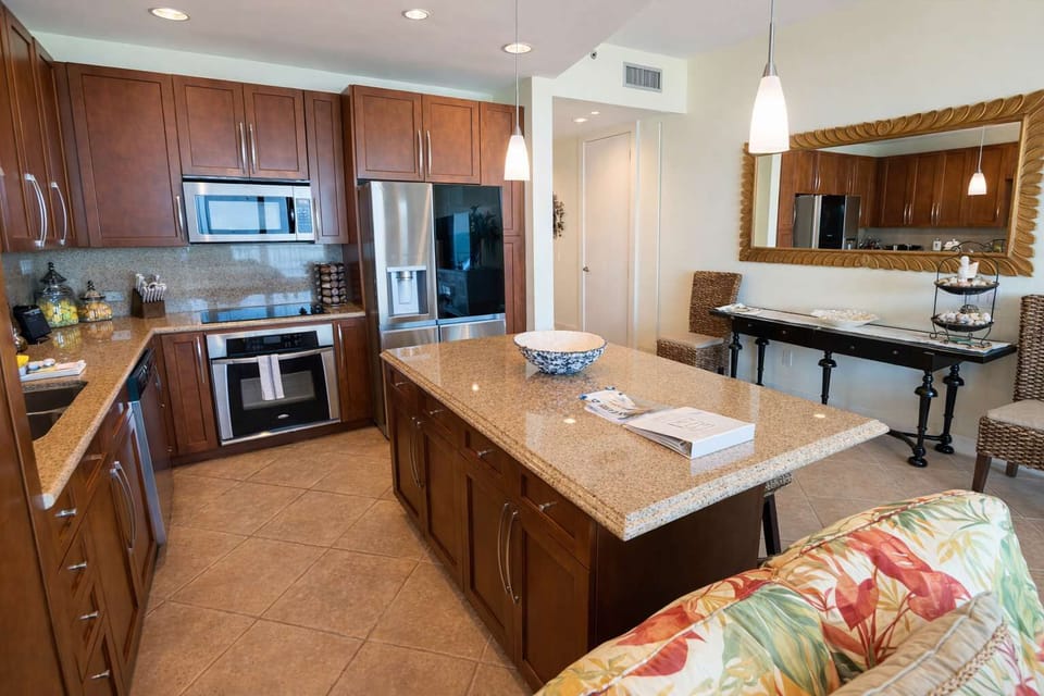 Modern Island Kitchen + Tropical Touches Near Beach  
Warm wood cabinetry, granite counters, stainless steel appliances, and inviting decor—perfect for relaxing, cooking, and entertaining in a coastal retreat.