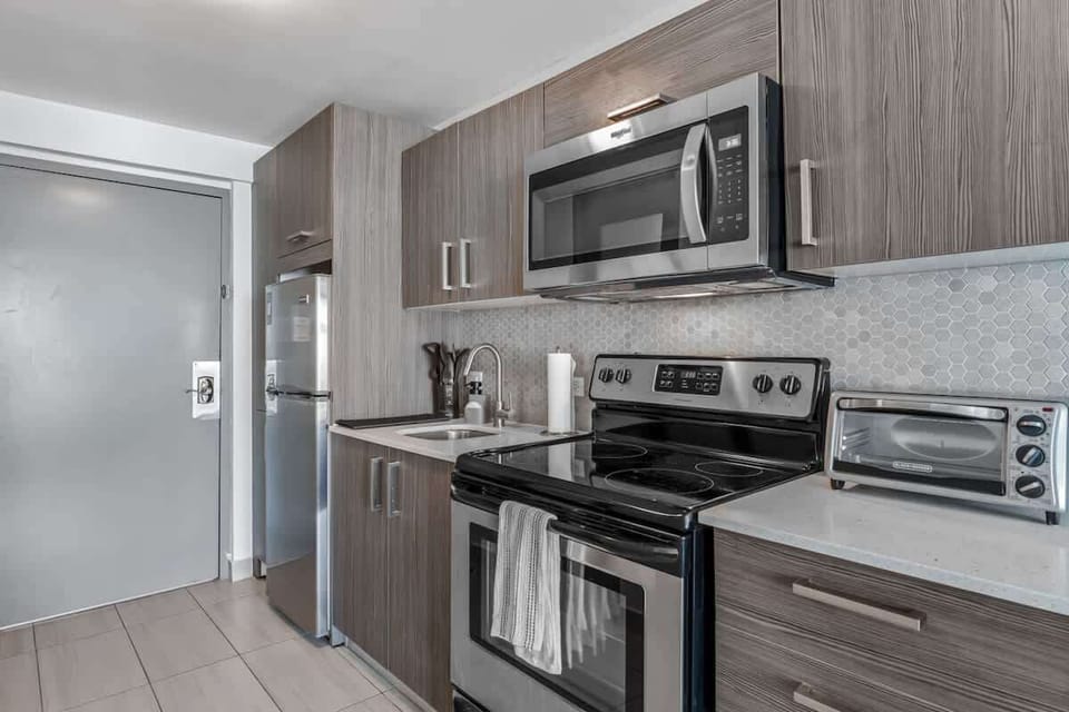 The kitchen has a light-toned countertop and a decorative, textured backsplash.