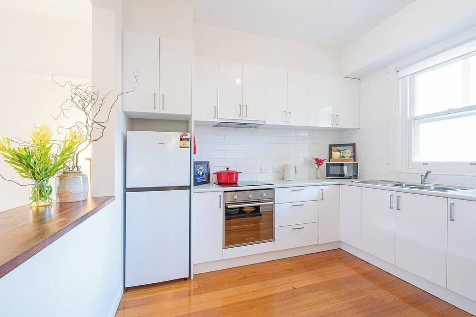 The kitchen is fully equipped with sleek white cabinetry, modern appliances including an oven, fridge, microwave and dishwasher, plus all the cooking basics to make daily routines feel effortless.