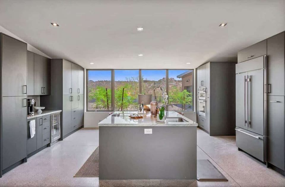 Estate 1: Fully equipped luxury kitchen stocked with all culinary essentials and features high-end stainless-steel appliances, a kitchen island, a breakfast table, and a wet bar / coffee station.