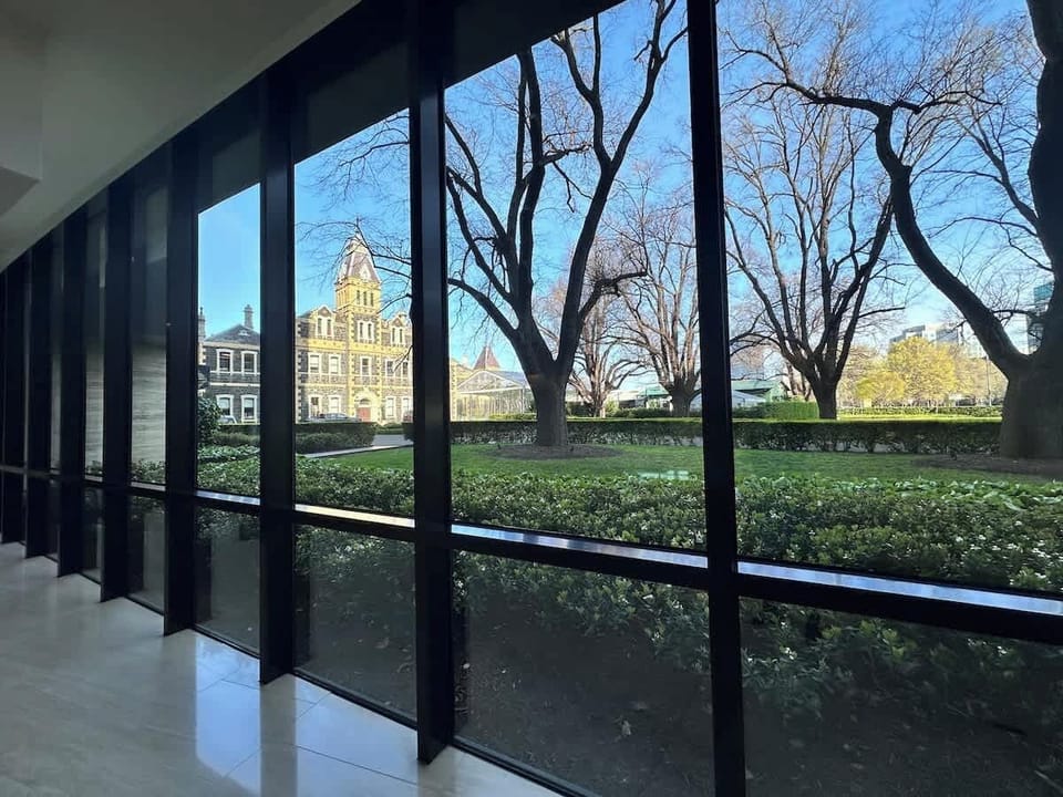 The spacious front yard, framed by vibrant hedges and mature trees, offers privacy and a natural connection. The sleek architecture, enhanced by large reflective windows, seamlessly blends indoor and outdoor spaces.